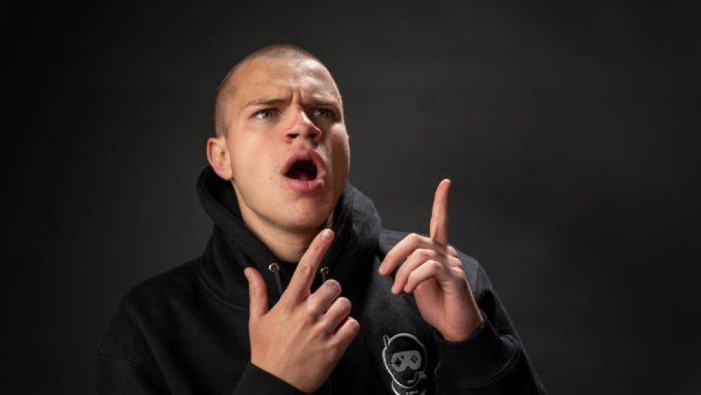 Twitch streamer Jynxzi posing with his fingers up in a dark room.